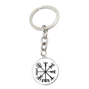 Détail d'un porte-clés boussole viking Vegvísir en métal sur fond blanc immaculé