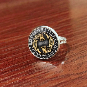 Makroaufnahme von Wikinger-Ring mit Odin-Symbolen und goldenen Tieren auf Holzdekor