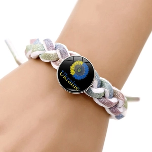 Gros plan d'un bracelet tressé avec pendentif tournesol Ukraine porté au poignet