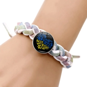 Détail d'un pendentif cœur papillon tournesol sur un bracelet tressé scintillant