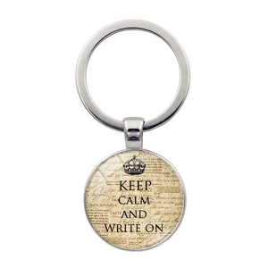 Macro detail of Keep Calm and Write On keychain pendant with vintage crown motif on white base