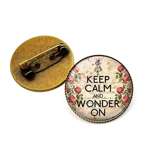 Vintage bronzen broche met Keep Calm and Wonder On-tekst en bloemenillustratie