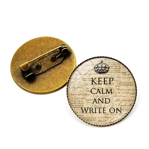 Detailopname van retro bronzen broche met Keep Calm tekst en veiligheidsspeldsluiting