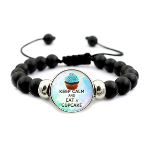 Detail eines schwarzen Perlenarmbands mit Cupcake-Anhänger und Keep-Calm-Slogan