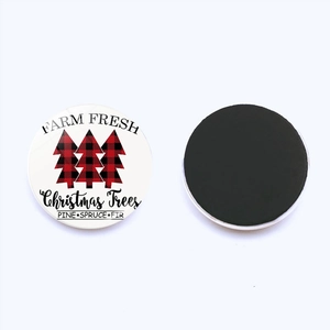 Detail of round Christmas fridge magnet showing front plaid trees and back magnetic surface