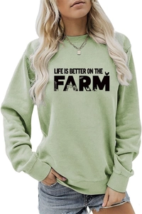 Close-up of light green farm sweatshirt with tractor and barn silhouettes design