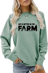 Close-up of sage green sweatshirt with artistic Life Is Better On The Farm print details