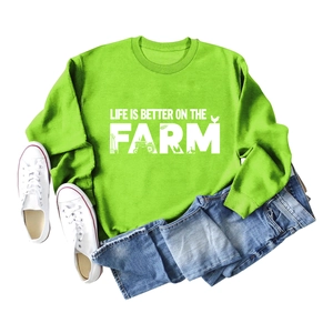 Detailed flat lay of a bright green fleece sweatshirt with 'Life is Better on the Farm' text