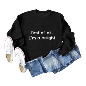 Detailed flat lay of black crewneck sweatshirt with First of all white script lettering
