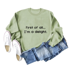 Flat lay of sage green sweatshirt with First of All slogan and casual denim outfit