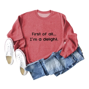 Detail showing the red crewneck sweatshirt with First of all text print and cotton texture