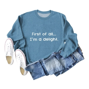 Flat lay of a blue crewneck sweatshirt with First of all text print and denim shorts