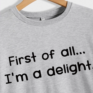 Grey crewneck sweatshirt with 'First of all' text print hanging on a wooden hanger