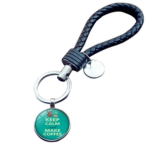 Detail of coffee themed keychain with black braided leather rope and glass charm