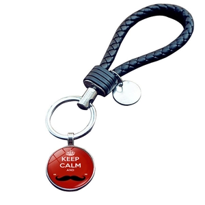 Detail of red crown pendant on black braided leather keychain with Keep Calm text