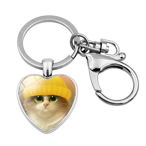 Detail of heart-shaped keychain featuring a cat in a yellow hat with a lobster clasp