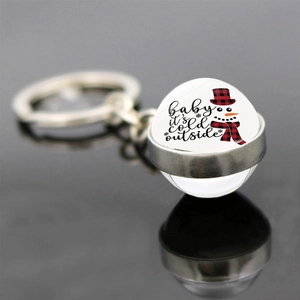 Detail of Christmas keychain with glass cabochon featuring a snowman and festive text
