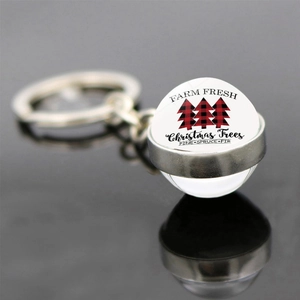 Close-up of silver Christmas keychain with buffalo plaid trees and mirror reflection