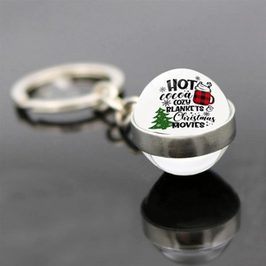 Detail of Christmas glass ball keychain with festive hot cocoa and tree graphic