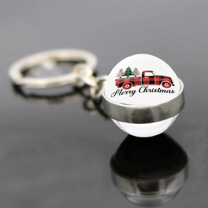 Detail shot of a double-sided Christmas glass ball keychain with a festive truck and tree