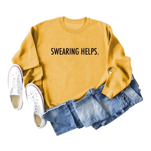 Détail de l'imprimé Swearing Helps sur un sweat jaune moutarde et jean bleu