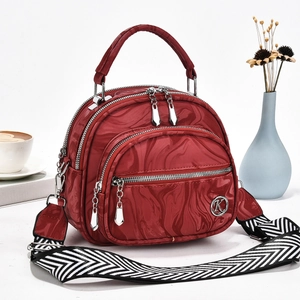 Detail of dark red marble pattern handbag with multi-layer zippers and woven strap