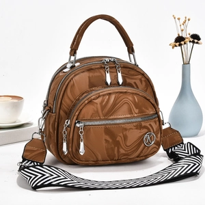 Detail view of glossy brown marble textured handbag with metal K logo and woven strap
