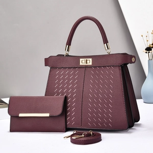 Detail of burgundy wine leather tote with diagonal texture and gold twist-lock closure