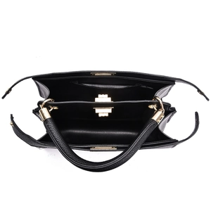 Macro view of black pebbled leather handbag interior with gold zippers and compartments