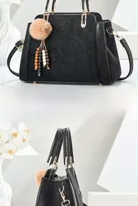 Détail d'un grand sac cabas noir avec pompon en peluche et pendentif à pampilles