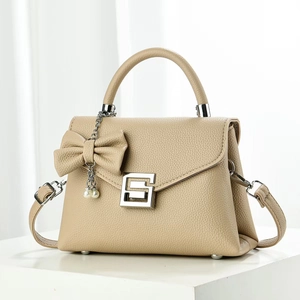Detail der beigen Tasche aus genarbtem Leder mit Schleife, Perle und silberner Schnalle