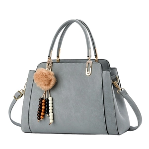Sac à main gris en cuir synthétique avec pompon décoratif et finitions dorées chic
