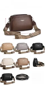 Detail view of leather crossbody bag with three zippers and wide jacquard strap