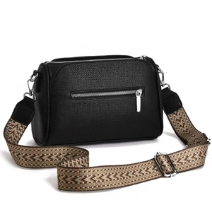 Detail of black lychee textured leather bag with vintage geometric woven shoulder strap