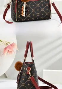 Detail of elegant patterned tote bag with red leather handles and plush ball charm