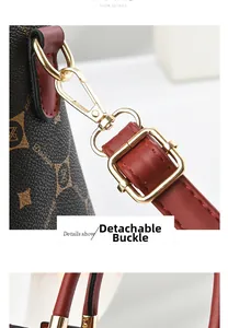 Close-up of the removable golden buckle and red leather strap on the brown monogram bag