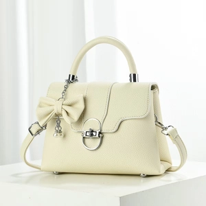 Detail of creamy white faux leather tote with silver ring lock and pearl bow charm