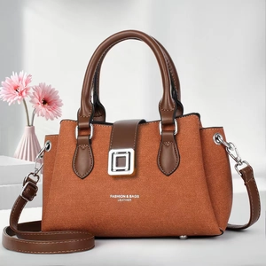 Detail of a stylish brown tote bag with silver metal buckle and floral background