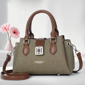 Detail of elegant khaki canvas tote with brown leather handles and silver metal buckle