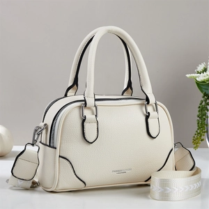Détail du sac bowling en cuir crème avec une large bandoulière au motif géométrique chic
