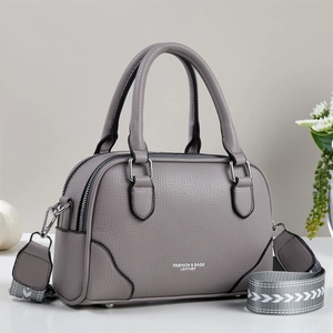 Détail du sac Boston en cuir gris avec bandoulière tissée et fermoirs argentés