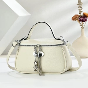 Detail of cream white leather handbag with litchi texture and silver bear charm
