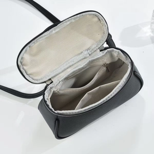 Detail view of the black crossbody bag interior with dual compartments and grey lining