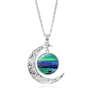 Detail of silver hollow moon pendant featuring aurora borealis glass stone and mountain scene