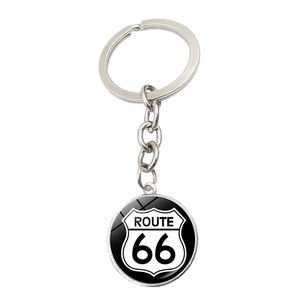 Gros plan d'un pendentif Route 66 en verre sur un porte-clés argenté fond blanc pur