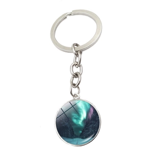 Macro detail of aurora borealis glass gem pendant with snowy forest and silver keyring