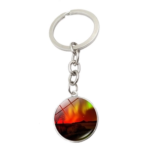 Detail of silver aurora borealis keychain with glass pendant and forest silhouette