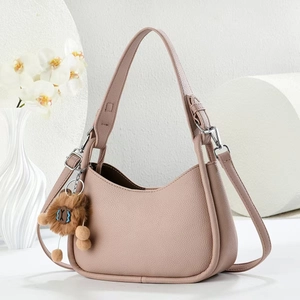 Détail du sac bandoulière en cuir grainé mauve avec charm ours en peluche sur décor blanc