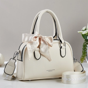 Detail of cream leather handbag with litchi texture and decorative floral bow charm