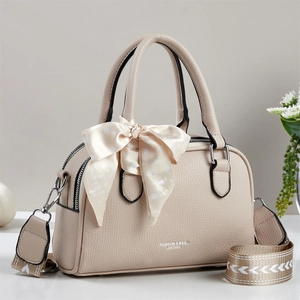 Detail of beige litchi grain leather Boston bag with polka dot silk ribbon and wide strap